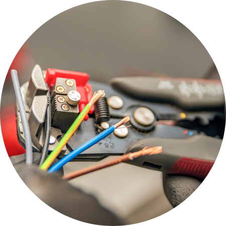 Nahaufnahme eines Werkzeugs zum Abisolieren von Kabeln, das mehrere bunte, bereits freigelegte Drähte festhält.